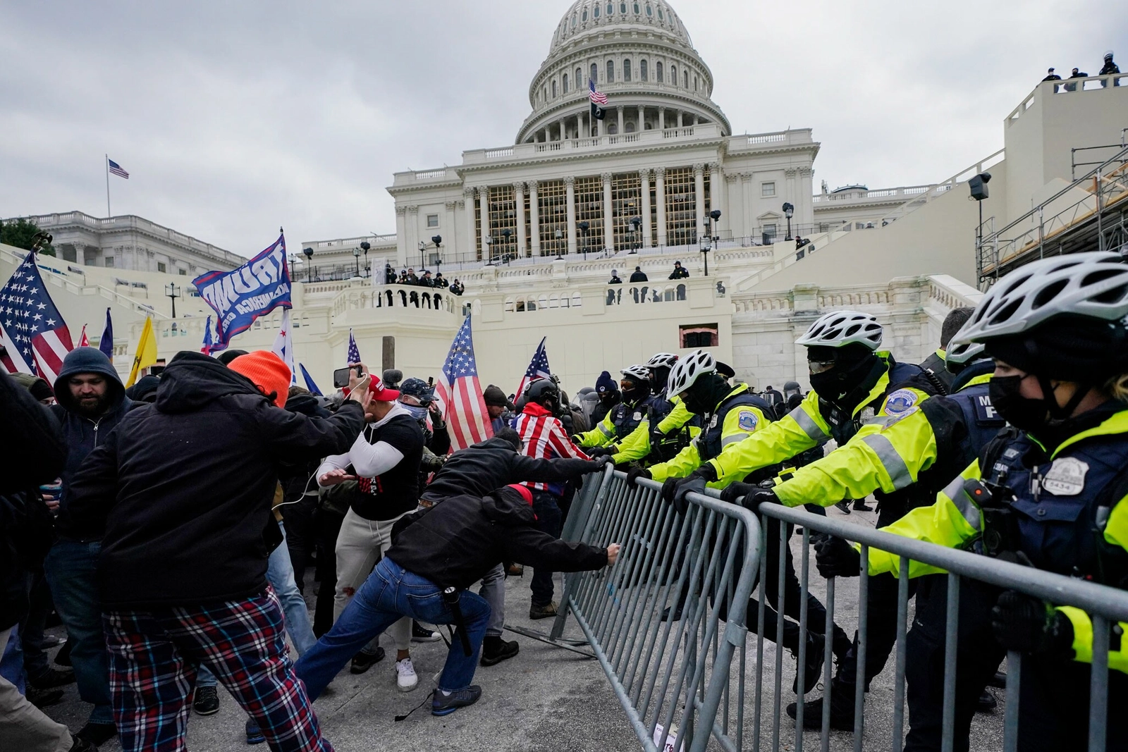 Una línea de agentes defiende una barricada de metal mientras los miembros de la turba intentan traspasarla y entrar en el Capitolio el 6 de enero del 2021. El jefe de la Policía del Capitolio dimitió al día siguiente. Fotografía de Julio Cortez, Ap